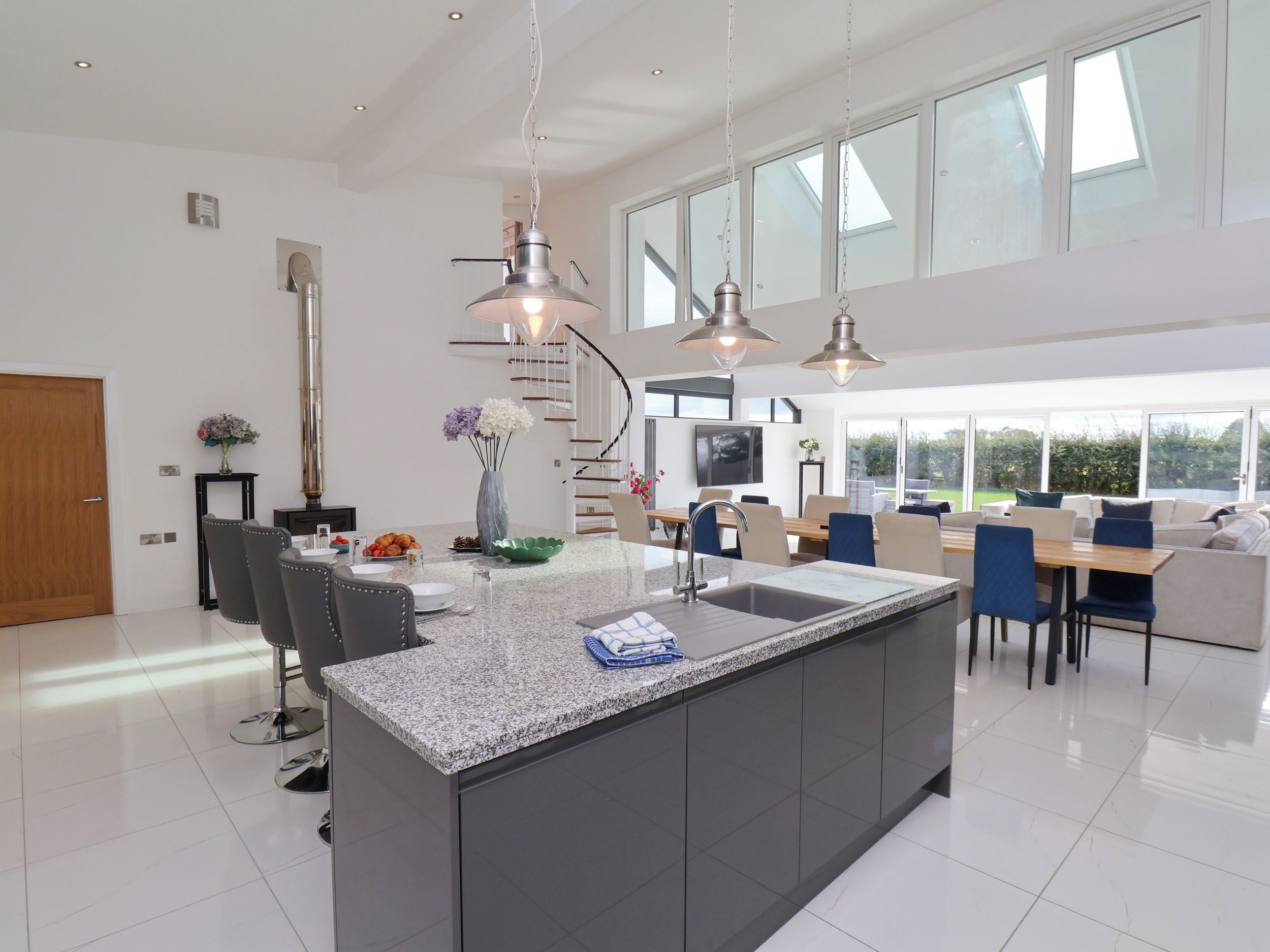 Una cocina amplia con una isla central, iluminación colgante moderna y un ventanal que proporciona luz natural.