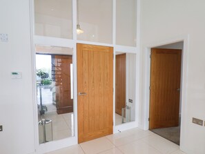 Un interior moderno con una puerta de madera, una puerta de cristal que da a un balcón y un suelo de baldosas.