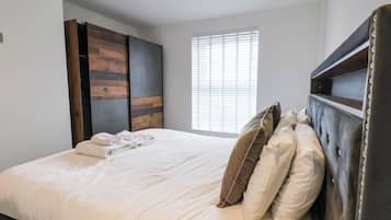 A bedroom with a bed, a wardrobe, and a window with blinds.