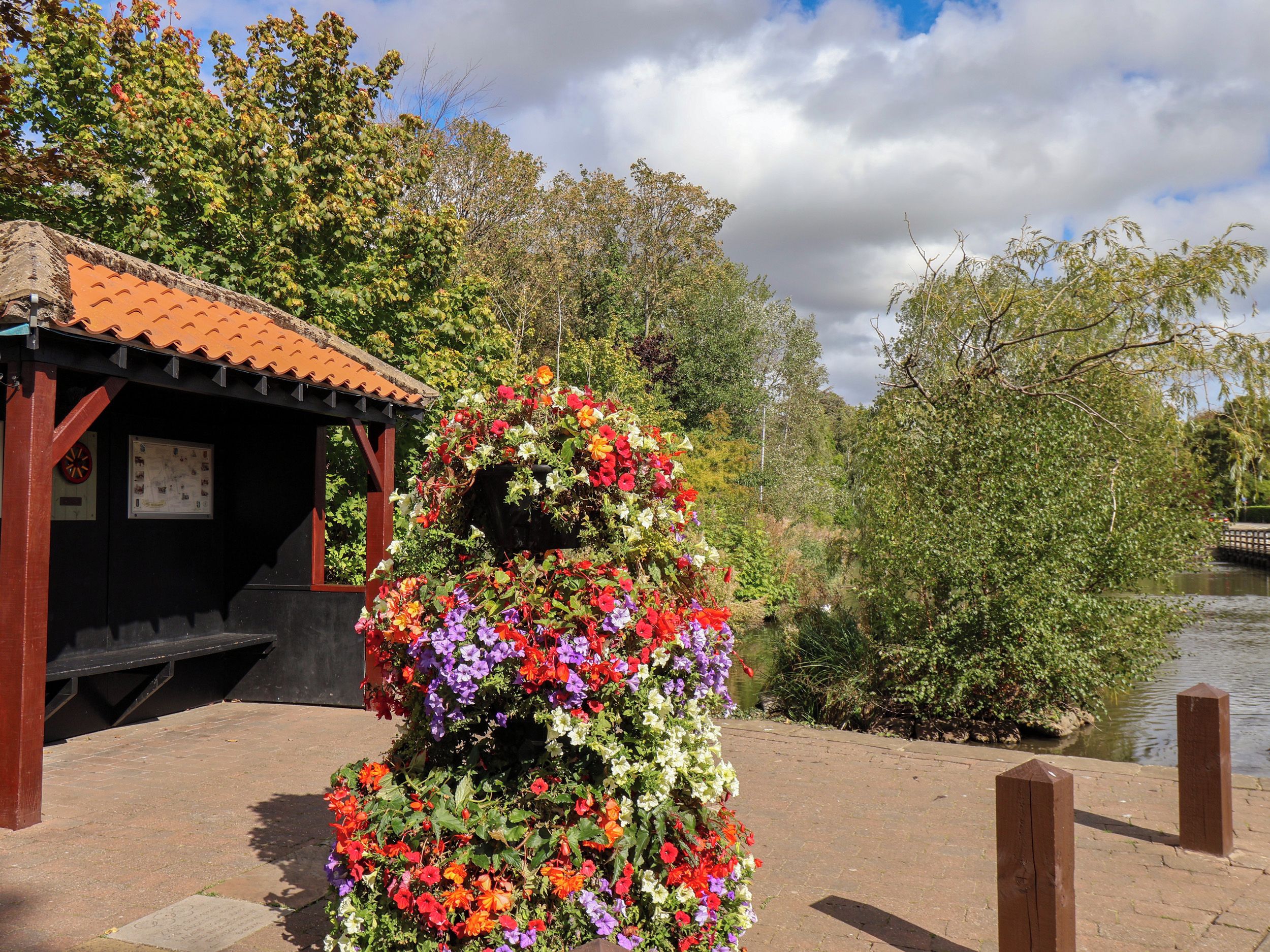 A garden with a variety of flowers and a gazebo with a tiled roof.