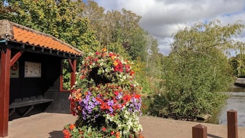A garden with a variety of flowers and a gazebo with a tiled roof.