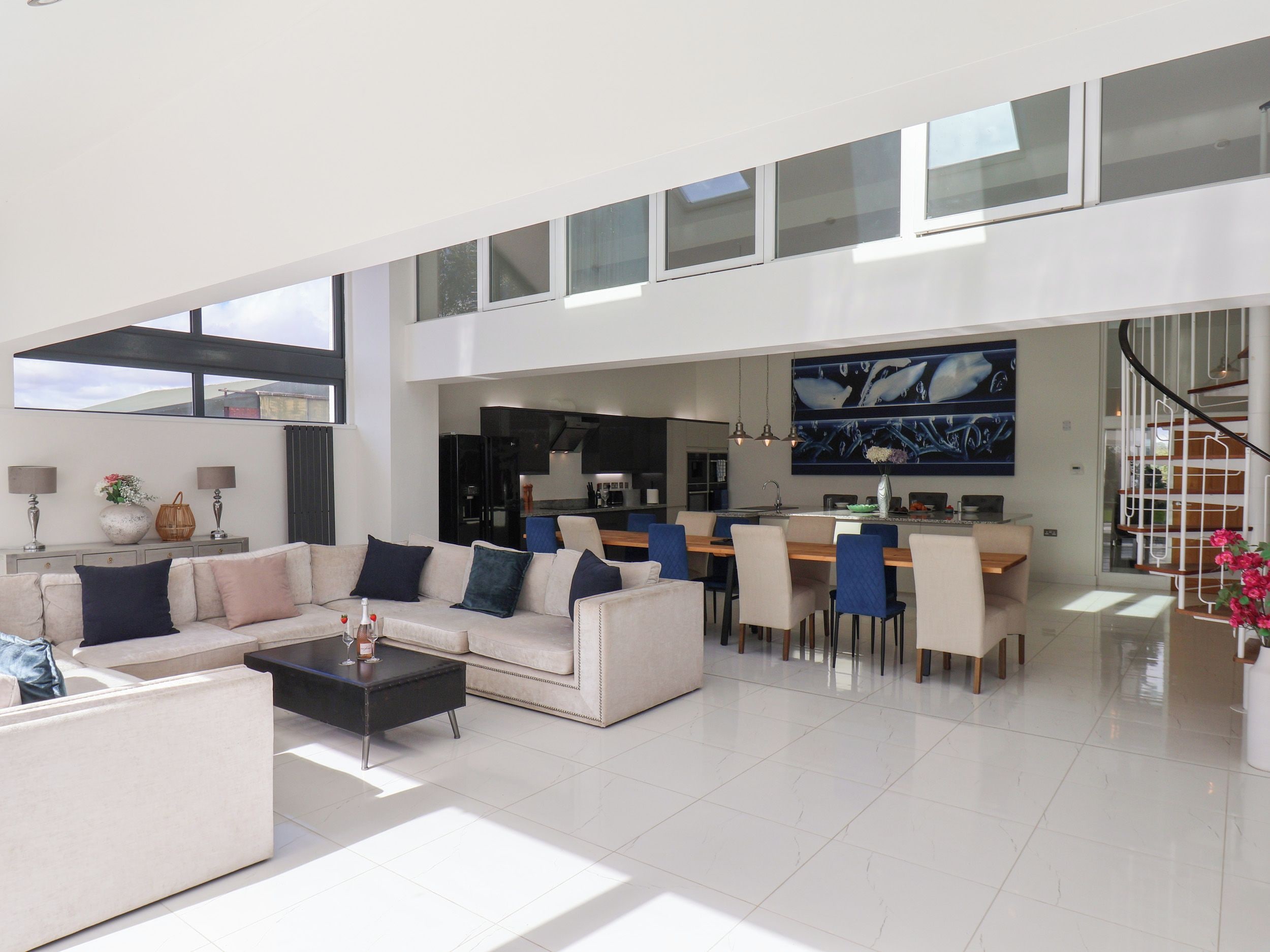 A spacious living area with a high ceiling, a dining area, and a kitchen.
