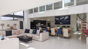 A spacious living area with a high ceiling, a dining area, and a kitchen.