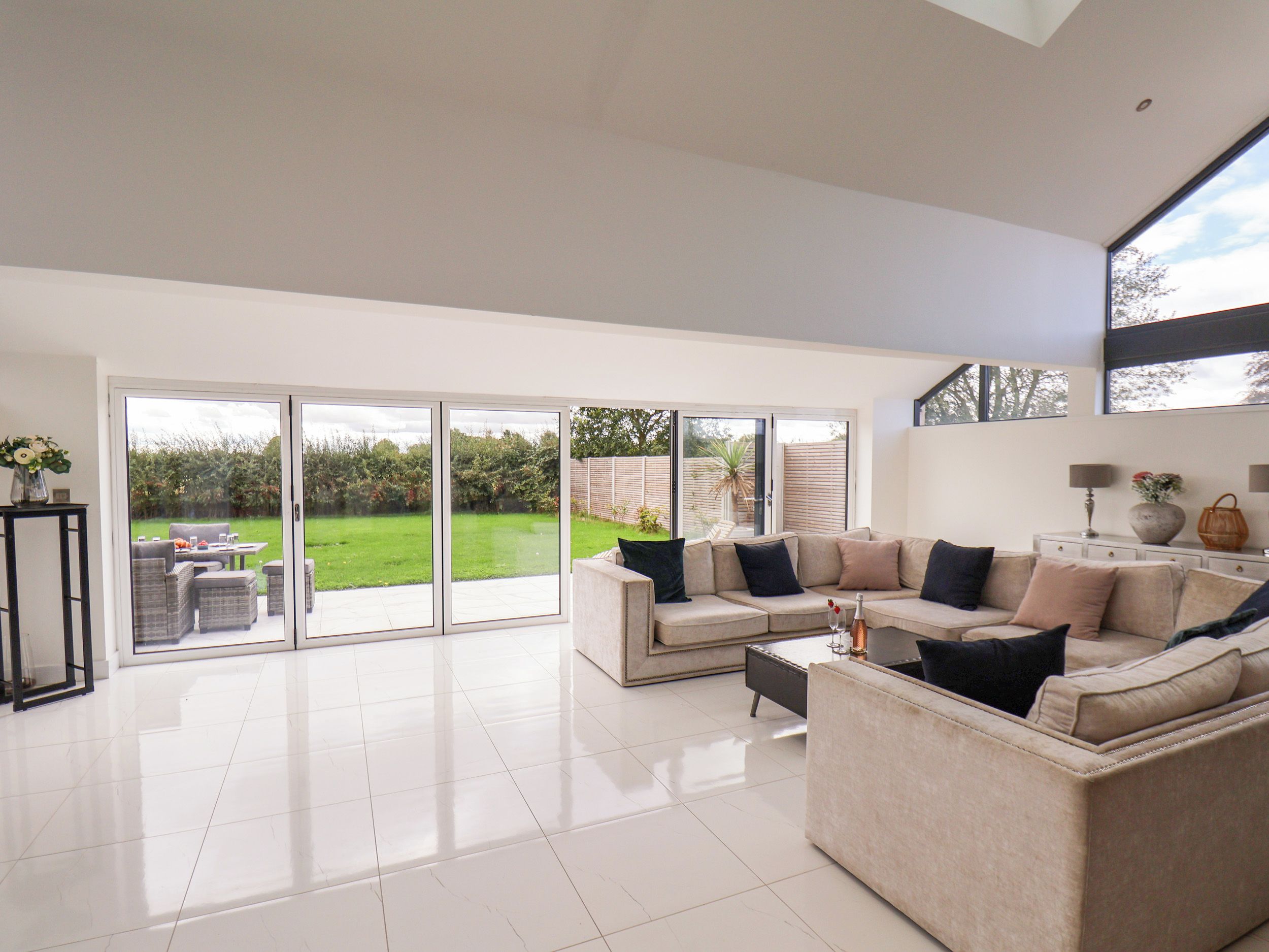 A spacious living room with a large sliding glass door leading to a garden.
