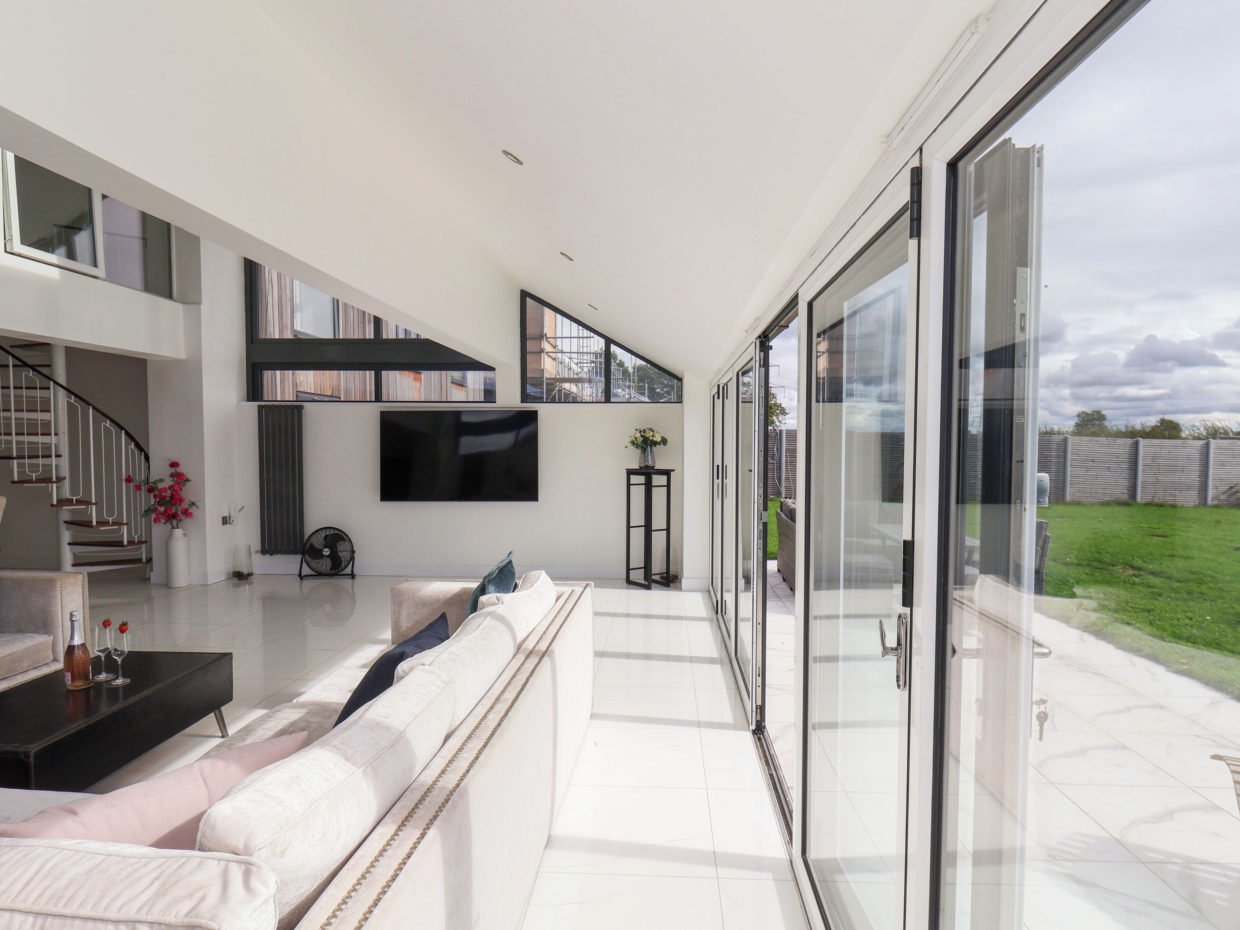 Una sala de estar moderna con un televisor de pantalla plana grande, un sofá y una escalera que conduce a un nivel superior.
