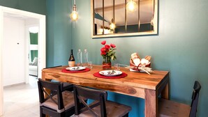 A dining area with a wooden table, two chairs, a vase with red flowers, a basket of bread, and a mirror above the table. - La Mansarda Chic by TuscanyWeGo (Prato)