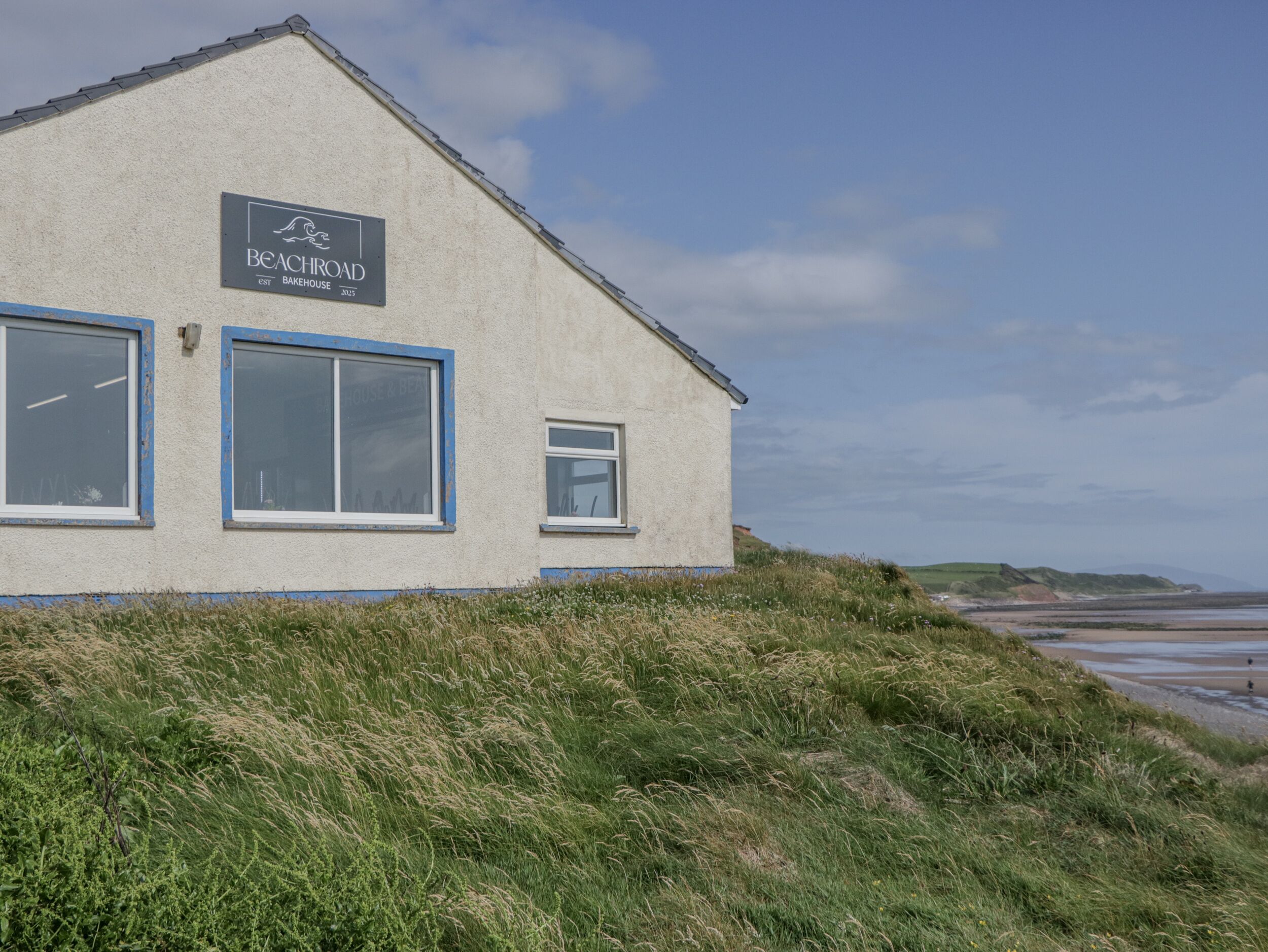 A building with a sign reading "Beach Road Bakehouse 2025" and two windows.