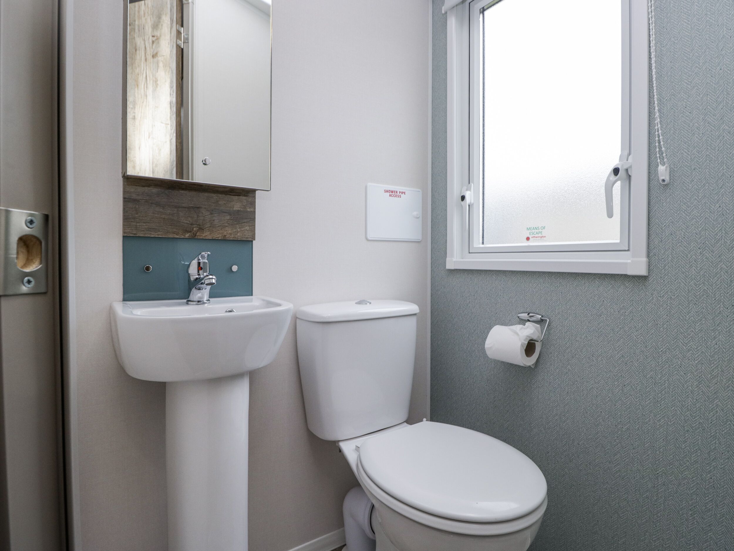 A bathroom with a sink, toilet, and a window with a towel hanging.
