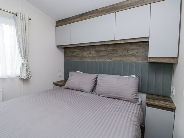 A bedroom with a bed, a nightstand, a wooden headboard, and a wardrobe.