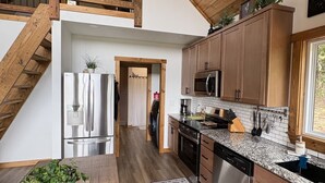 A modern kitchen with wooden beams, stainless steel appliances, and a large window.