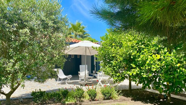 A patio area with a white umbrella, two white lounge chairs, and a small table. - House Apartment whole garden rai (Biarritz)