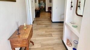 A hallway with a wooden floor, a table with a candle, and a mirror on the wall. - House Apartment whole garden rai (Biarritz)