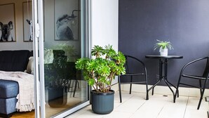 A modern living space with a sofa, a dining table, two chairs, and a potted plant. - Penny. 2BR Stylish Brunswick Stay w/ Parking (Brunswick)