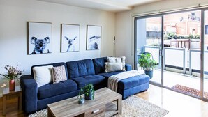 A modern living room with a blue sofa, a wooden coffee table, and three framed animal prints on the wall. - Penny. 2BR Stylish Brunswick Stay w/ Parking (Brunswick)