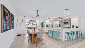 Une cuisine moderne dotée d’un îlot central, de tabourets de bar et d’un coin repas avec une table et des chaises en bois.