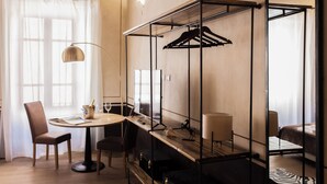 Et hotelværelse med et rundt spisebord, to stole, en hængende lampe, en trækommode, et spejl og en seng med et gulvtæppe med zebraprint.