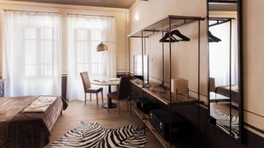 Et hotelværelse med en seng, et skrivebord med stol, et spejl og en måtte med zebrastriber.