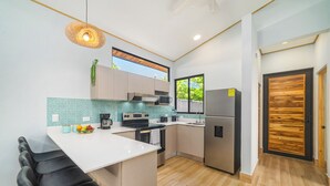 Una cocina moderna con una isla central, electrodomésticos de acero inoxidable y vistas al exterior.