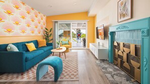 A living room with a blue sofa, a patterned wall, a teal fireplace, and a view through a glass door. - Pool house w/Playground, Mini Golf, King Bed (Chula Vista)