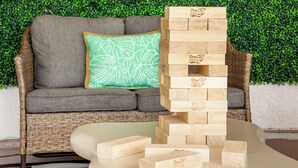 A Jenga tower on a white table with a green leafy wall and a sofa in the background. - Pool house w/Playground, Mini Golf, King Bed (Chula Vista)