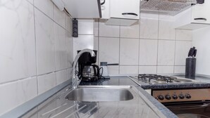 A kitchen with a stainless steel sink, a coffee maker, and a gas stove.