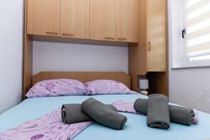 A single bed with a headboard, two pillows, and rolled towels on a blue bedspread. - A Apartment Near Beach With two Balconies (Kastela)