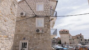 A stone building with a balcony, a door, and a small window.