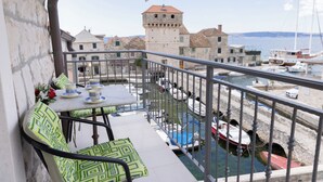 A balcony with a table and chairs, overlooking a marina with boats and historic buildings.