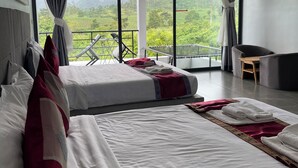 A hotel room with two beds, a balcony with a view of the countryside, and a seating area with a table and chairs. - HIDDEN LEAF RESORT (Veal Veaeng)