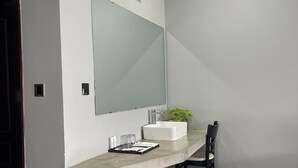 A modern bathroom with a large mirror, a white sink, a small plant, and a trash bin. - HIDDEN LEAF RESORT (Veal Veaeng)