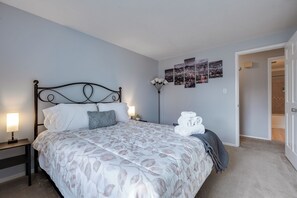 Une chambre à coucher bien rangée, avec un lit, des lampes de chevet et un luminaire fixé au mur.