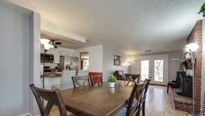 Ein Essbereich mit Holztisch und -stühlen, im Hintergrund eine Küche und ein Kamin aus Ziegelsteinen.