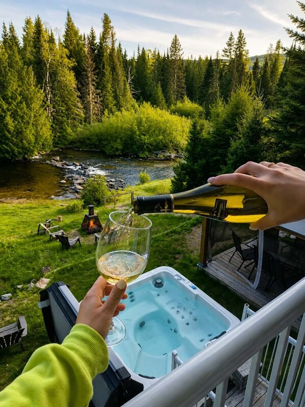 Un jacuzzi en una terraza con vistas a un bosque y un río.