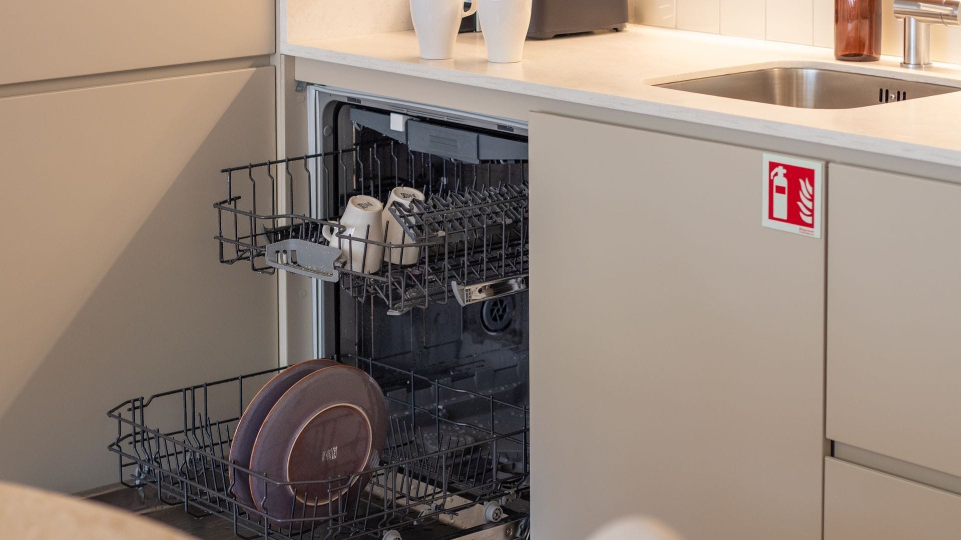A kitchen with a dishwasher, a sink, and a fire safety sign.