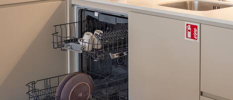 A kitchen with a dishwasher, a sink, and a fire safety sign.