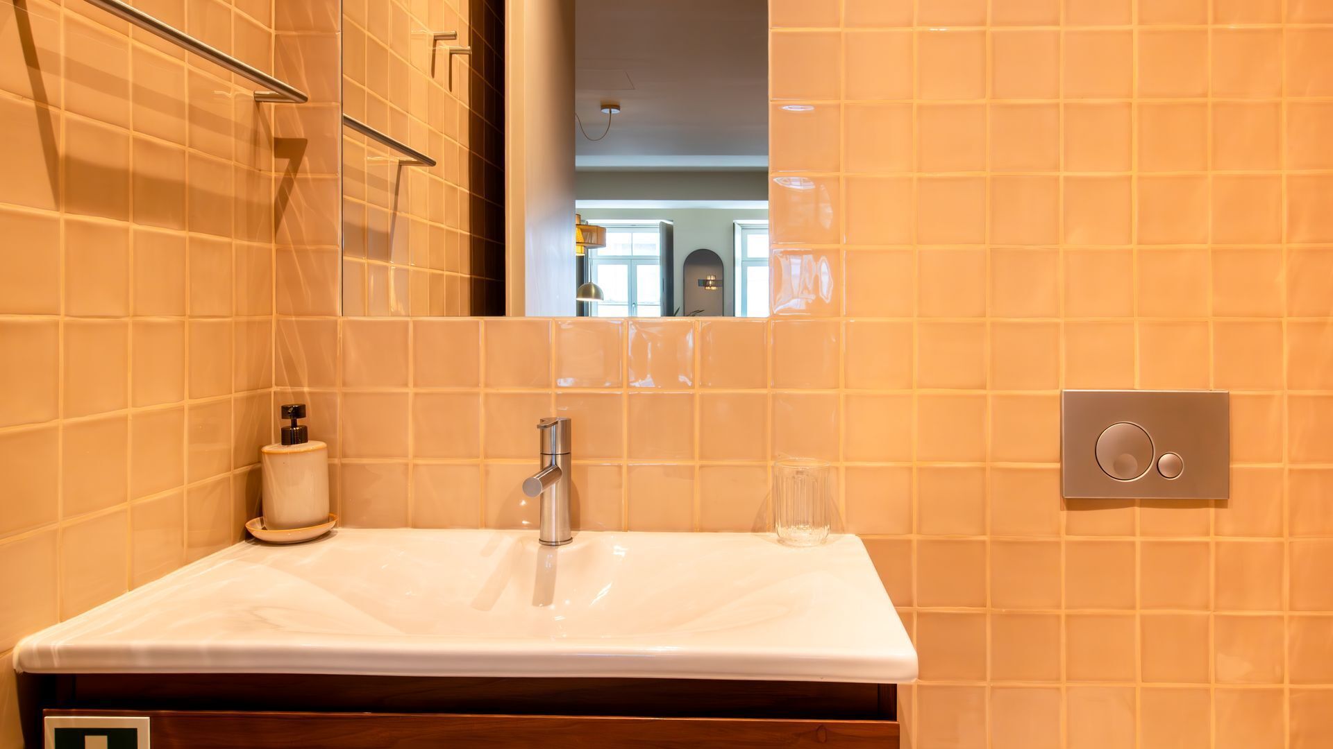 Ein Badezimmer mit einem weißen Waschbecken, einem Spiegel und einer Handseifenspender.