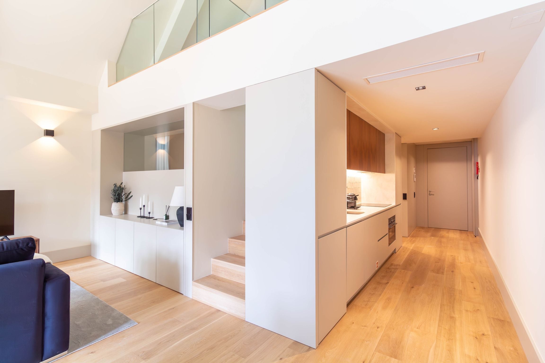 Un intérieur moderne comprenant un espace de vie, une cuisine et un escalier.