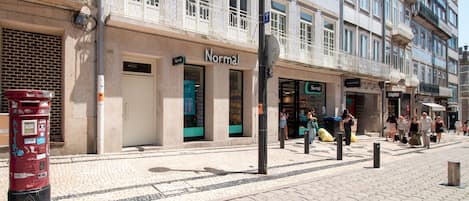 Una calle con una hilera de tiendas, incluyendo una tienda 'Normal' con escaparate verde.