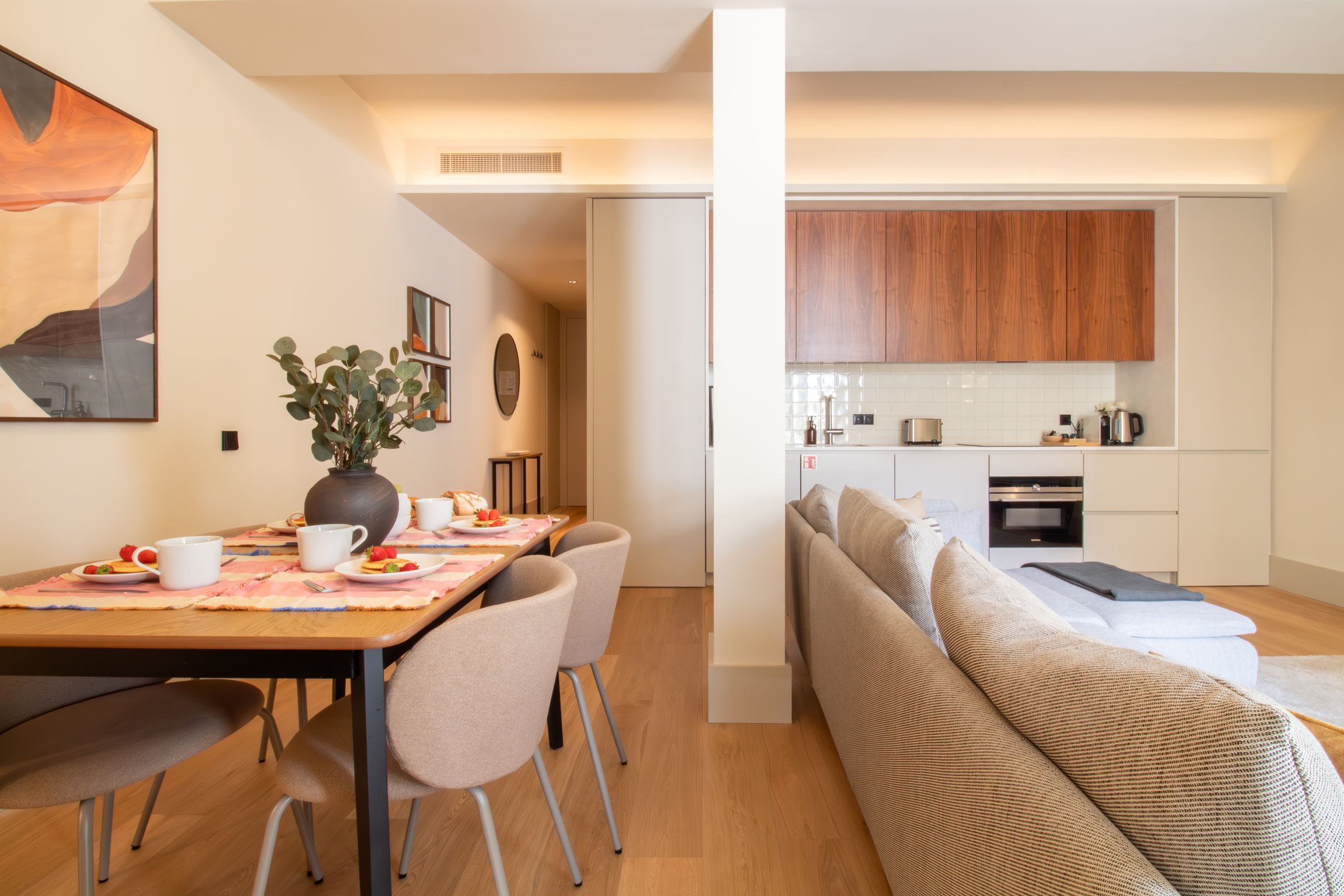 Eine moderne Wohnung mit Essbereich, einer Küchenzeile und einem Wohnraum mit Sofa.