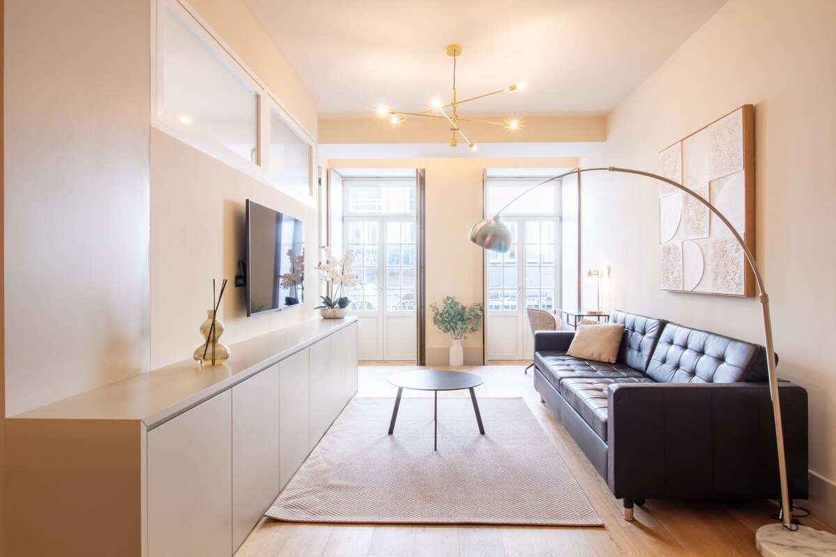 A modern living space with a kitchen, a sofa, a dining area, and a large window.