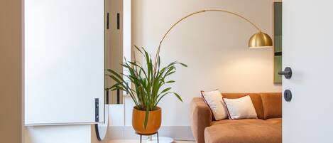 Una sala moderna con un sofá marrón, una planta en maceta y una lámpara de pie.