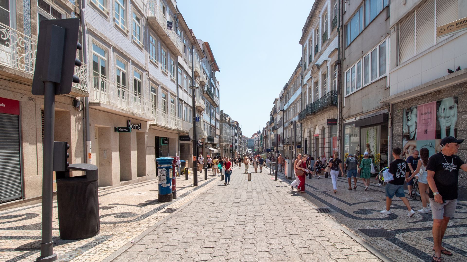 A cobblestone street lined with historic buildings, some with balconies and signage.