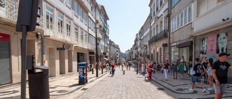 A cobblestone street lined with historic buildings, some with balconies and signage.