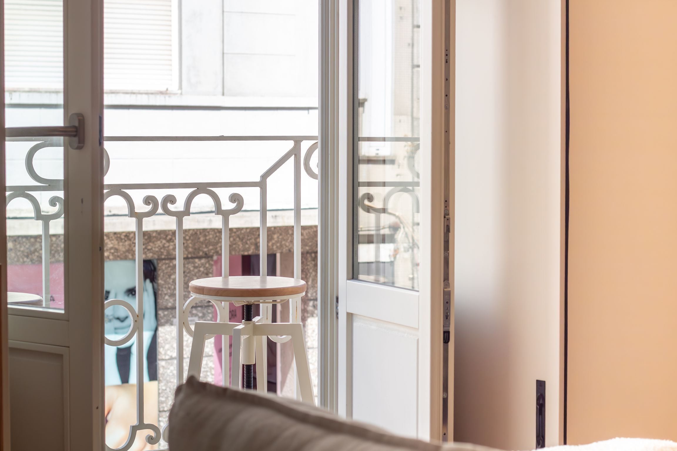 A balcony with a white metal railing, a small round table, and a chair.