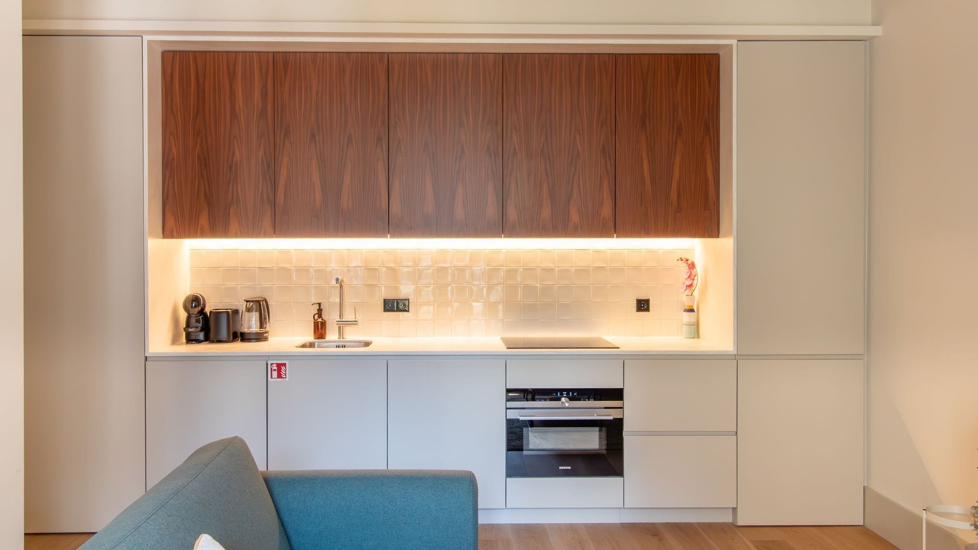 Une cuisine moderne avec des meubles en bois, un plan de travail blanc et un four Siemens.