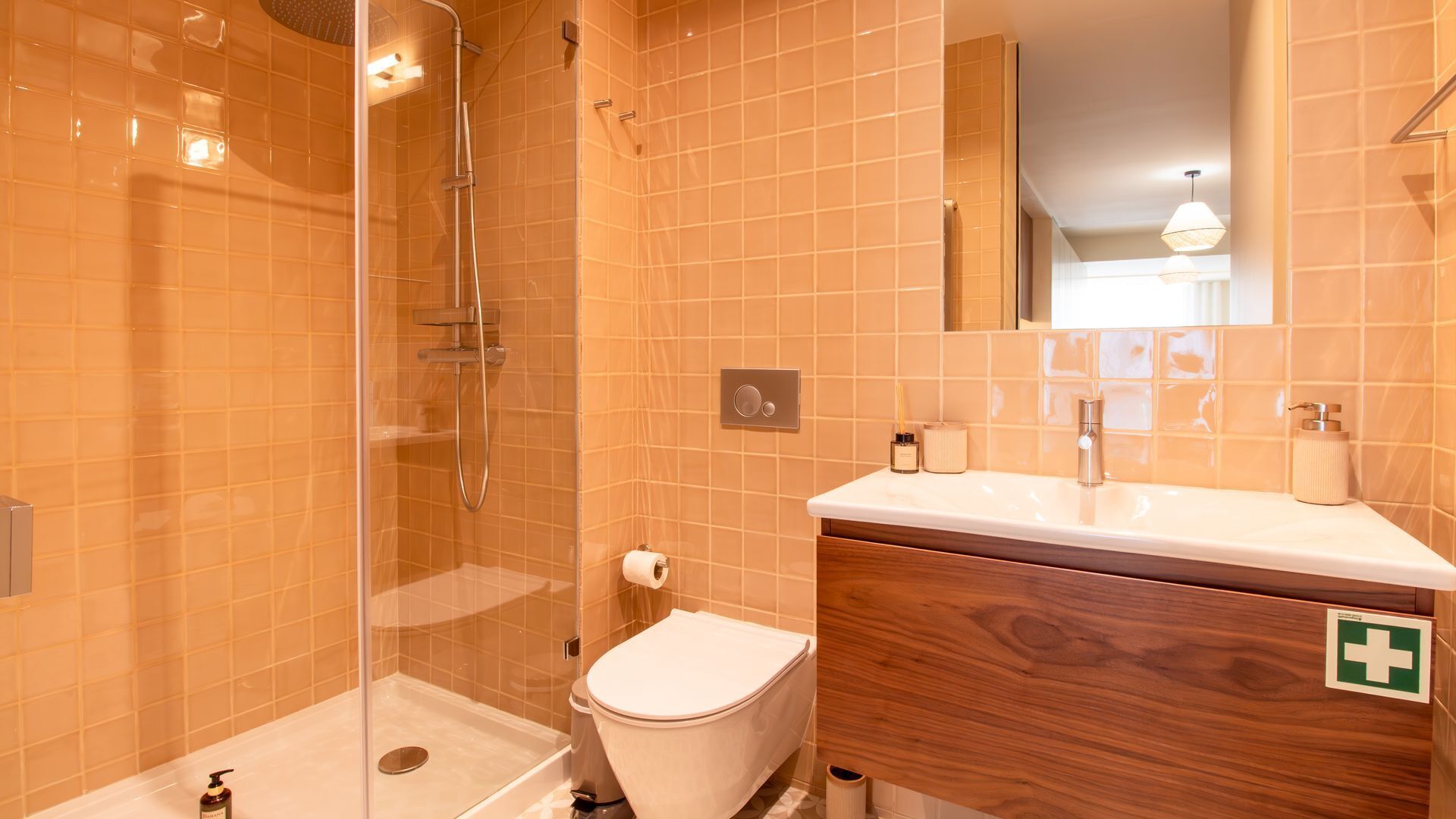 A bathroom with a glass-enclosed shower, a toilet, a sink with a mirror, and a wooden vanity.