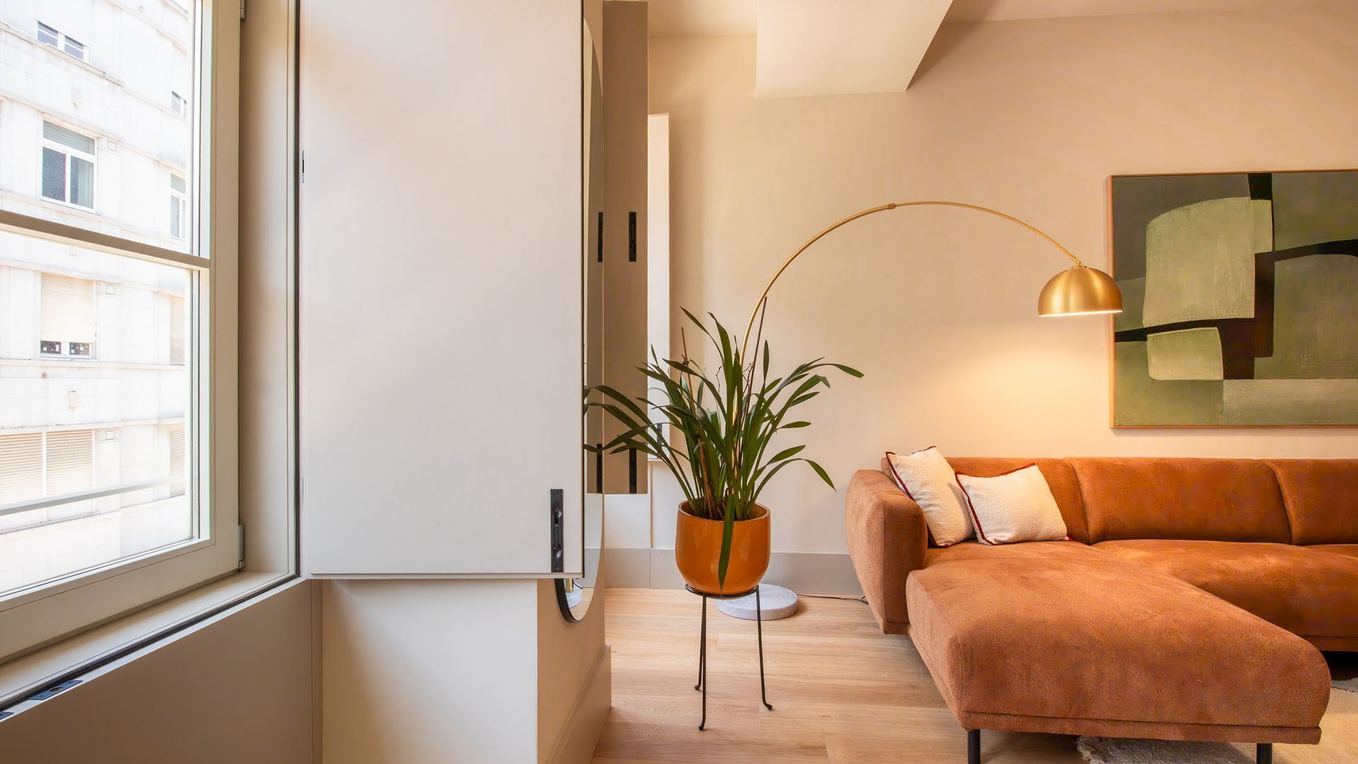 Een moderne woonkamer met een bank, een vloerlamp en een plant in pot.
