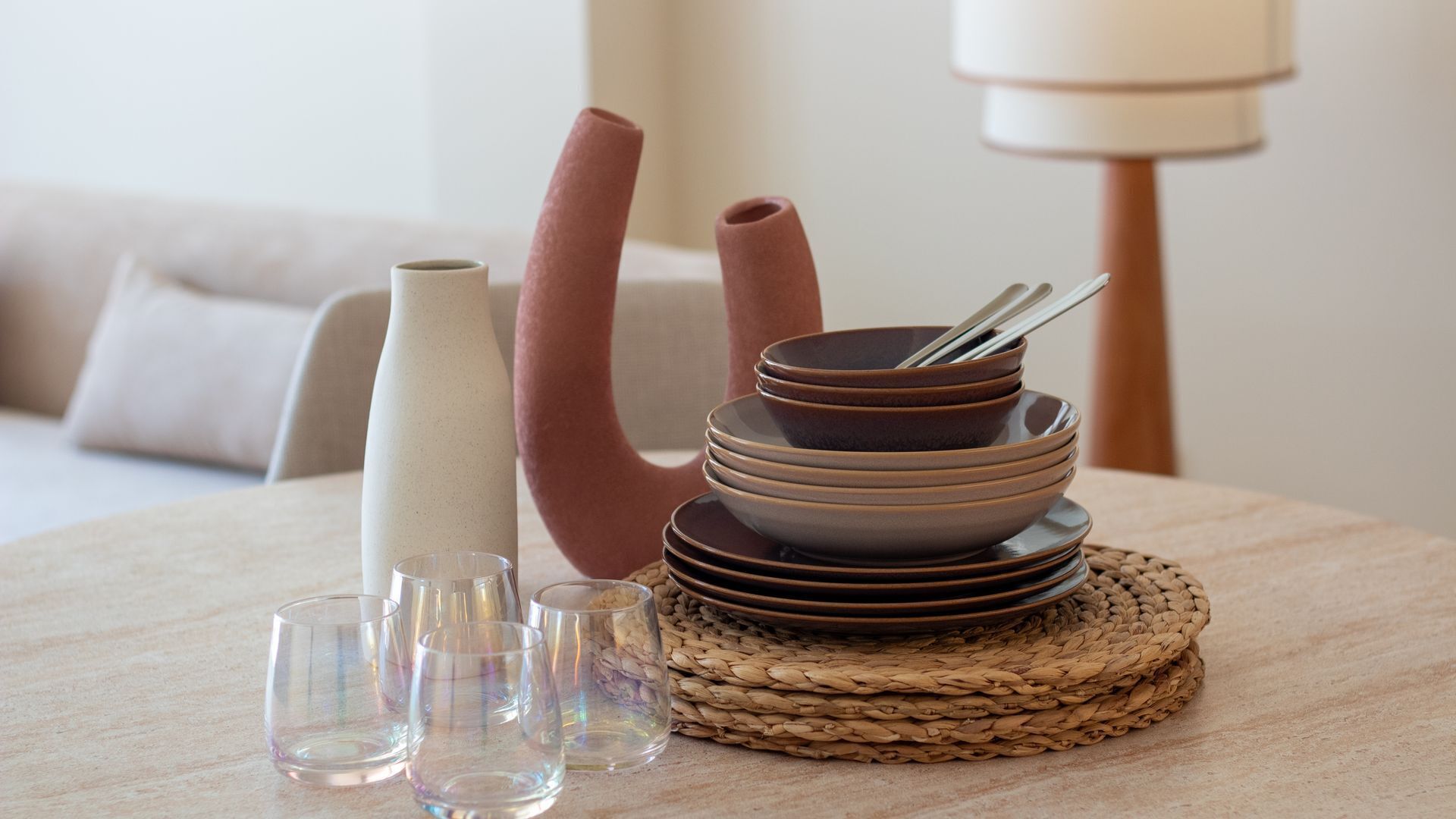 A dining table with stacked plates, a vase, and glasses.