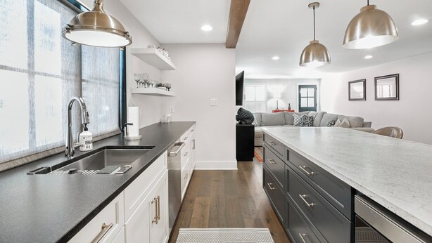 Una cocina moderna con una isla grande, electrodomésticos de acero inoxidable e iluminación colgante.