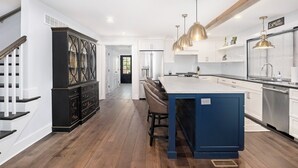 Una cocina moderna con una isla central, iluminación colgante y estufa integrada.